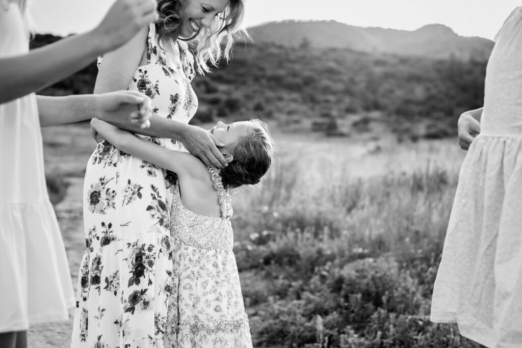 Little girl giving her mom a hug around the waste and staring up at her eyes with a smile.