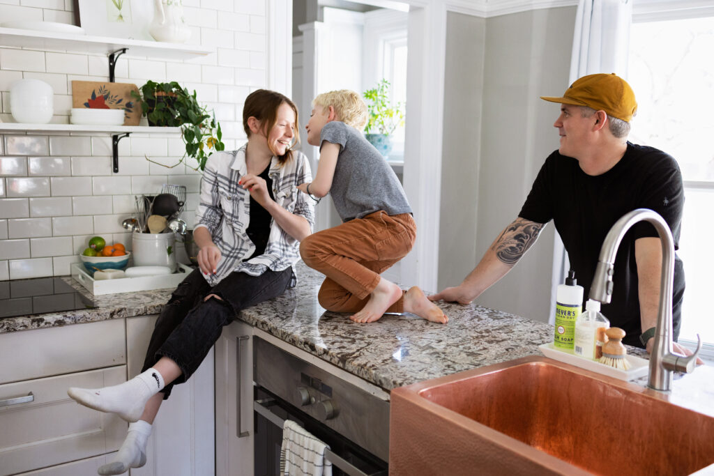 Brother and sister on kitchen counter playing with Dad watching.