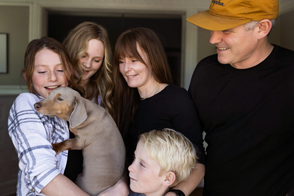 Family snuggling with their dog in their home.