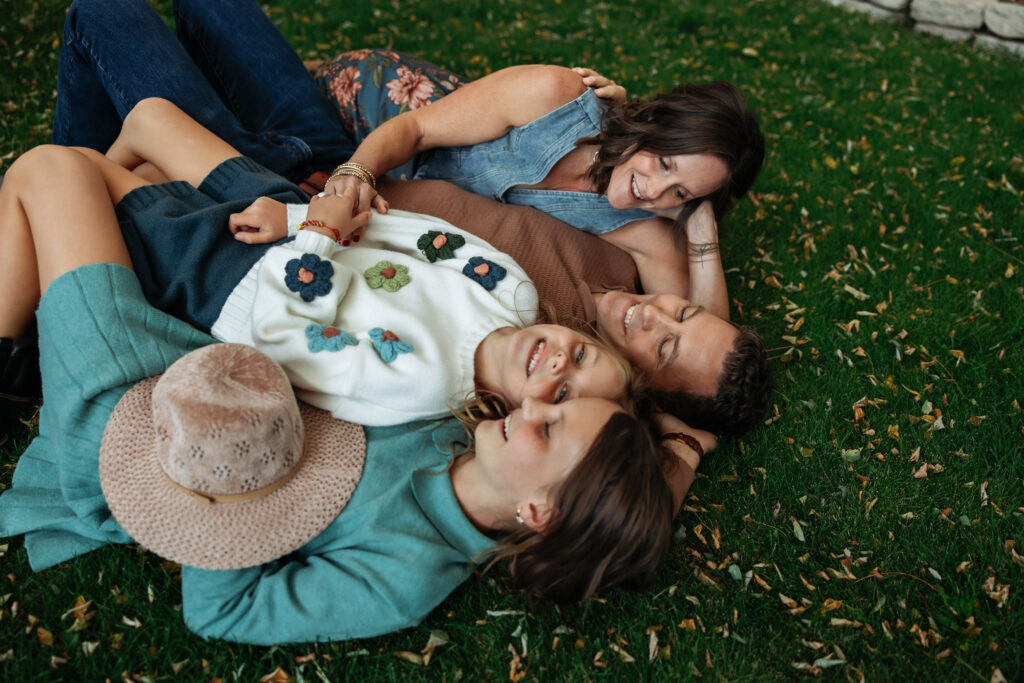 Family of four snuggled on the grass.