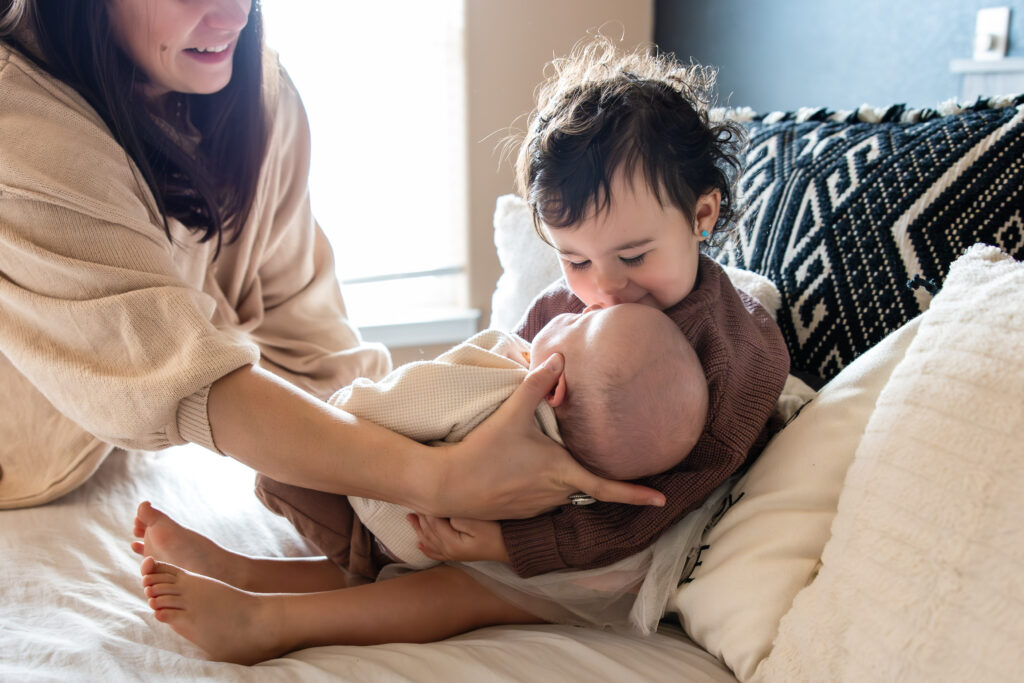 Big sister holding newborn baby brother at an in-home photography session near Colorado Springs.