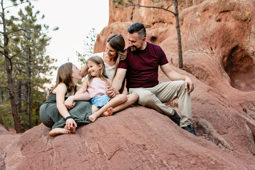 Family of four snuggled on beautiful red rocks in beautiful Colorado Springs location.