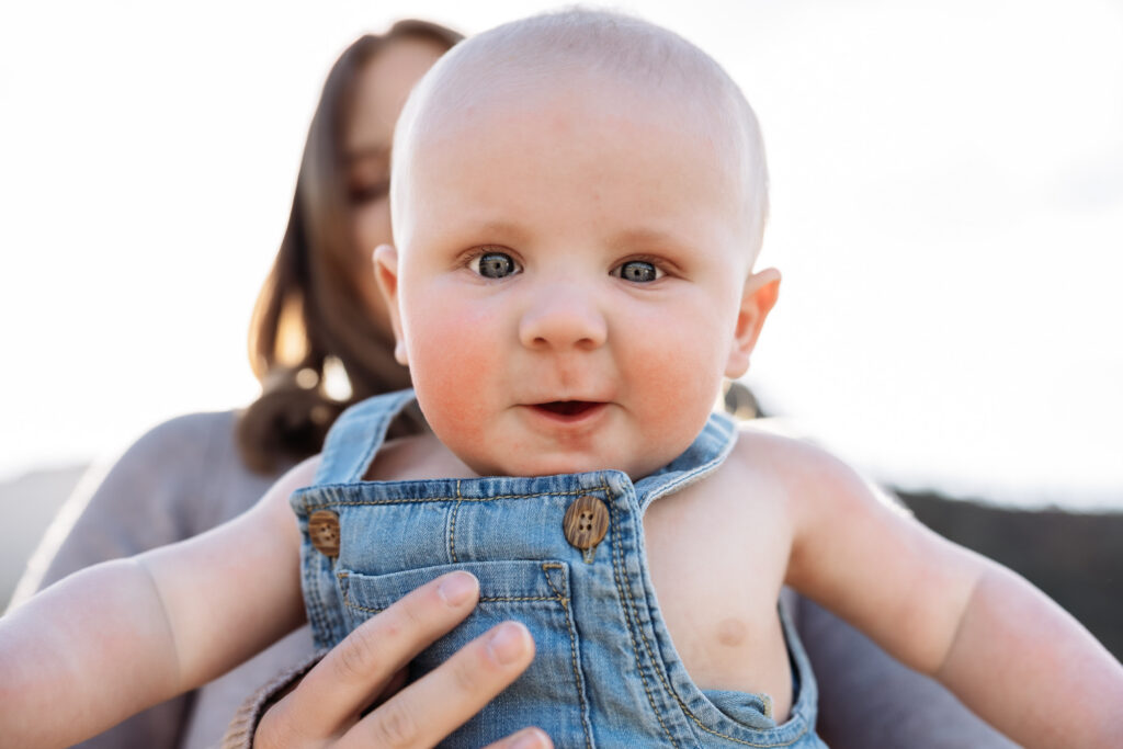 Close up of six month old baby flying in the air at baby photo session in Colorado Springs.