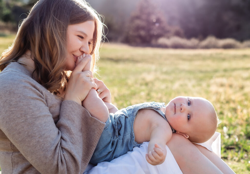A mom in Colorado Springs kisses her baby's feet while holding him in her lap.