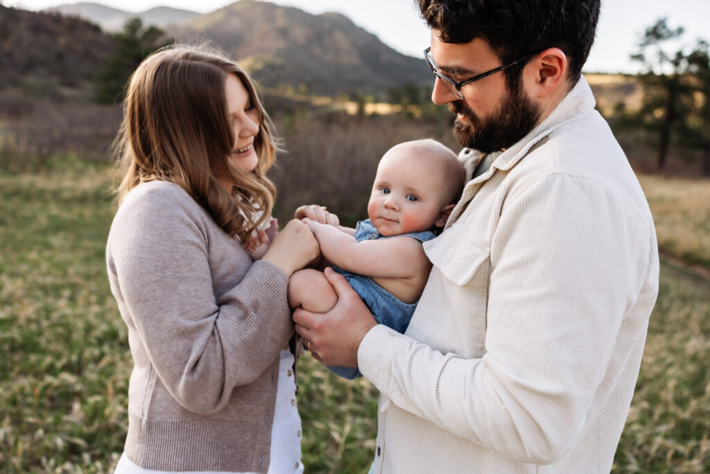 Mom and Dad admire their baby while they hold him at a photo session in Colorado Springs.
